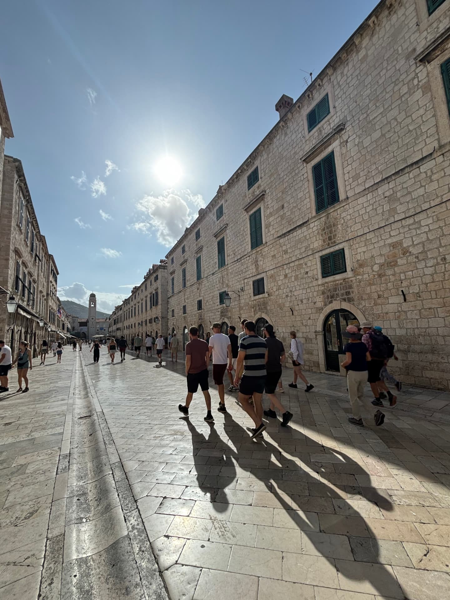 Kollegor promenerar på en solig stenlagd gata i Dubrovniks gamla stan